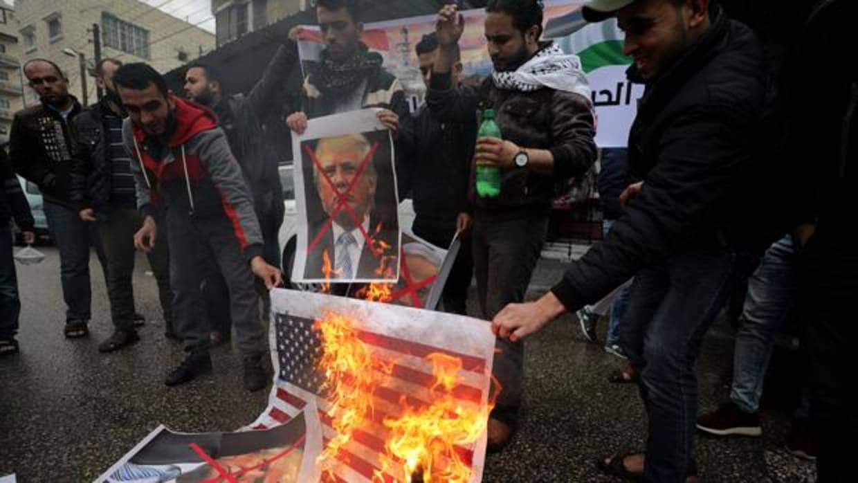 Palestinos queman una bandera estadounidense y retratos del presidente Trump, durante una protesta contra el reconocimiento de Jerusalén como capital de Israel