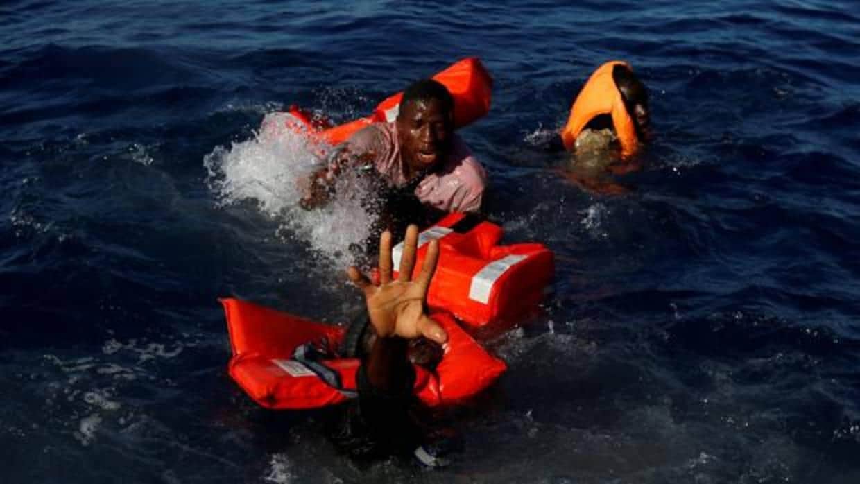 Fotografía de archivo de inmigrantes cuya embarcación ha naufragado e intentan salir a flote frente a las costas de Libia, en el Mediterráneo