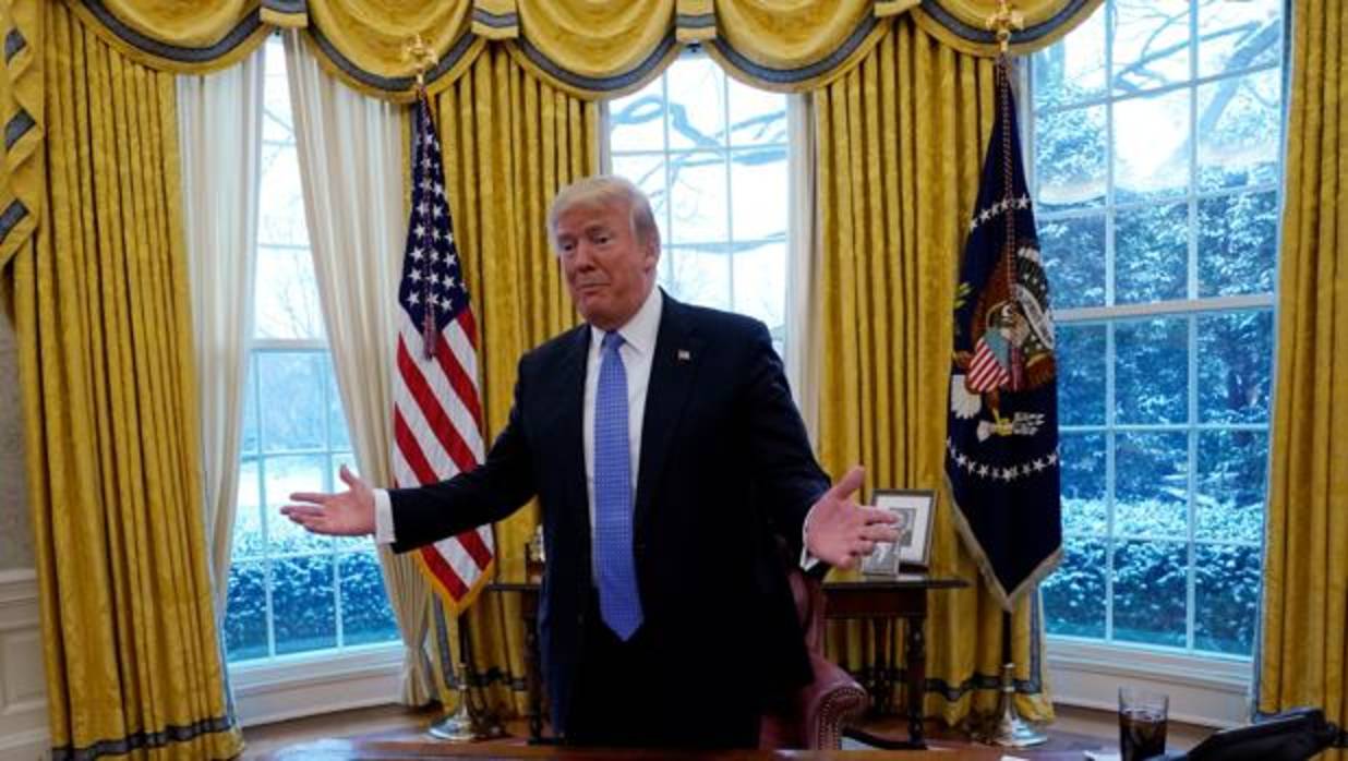 Donald Trump aparece en el Despacho Oval junto a su mesa, sobre la que tiene un vaso de su bebida favorita