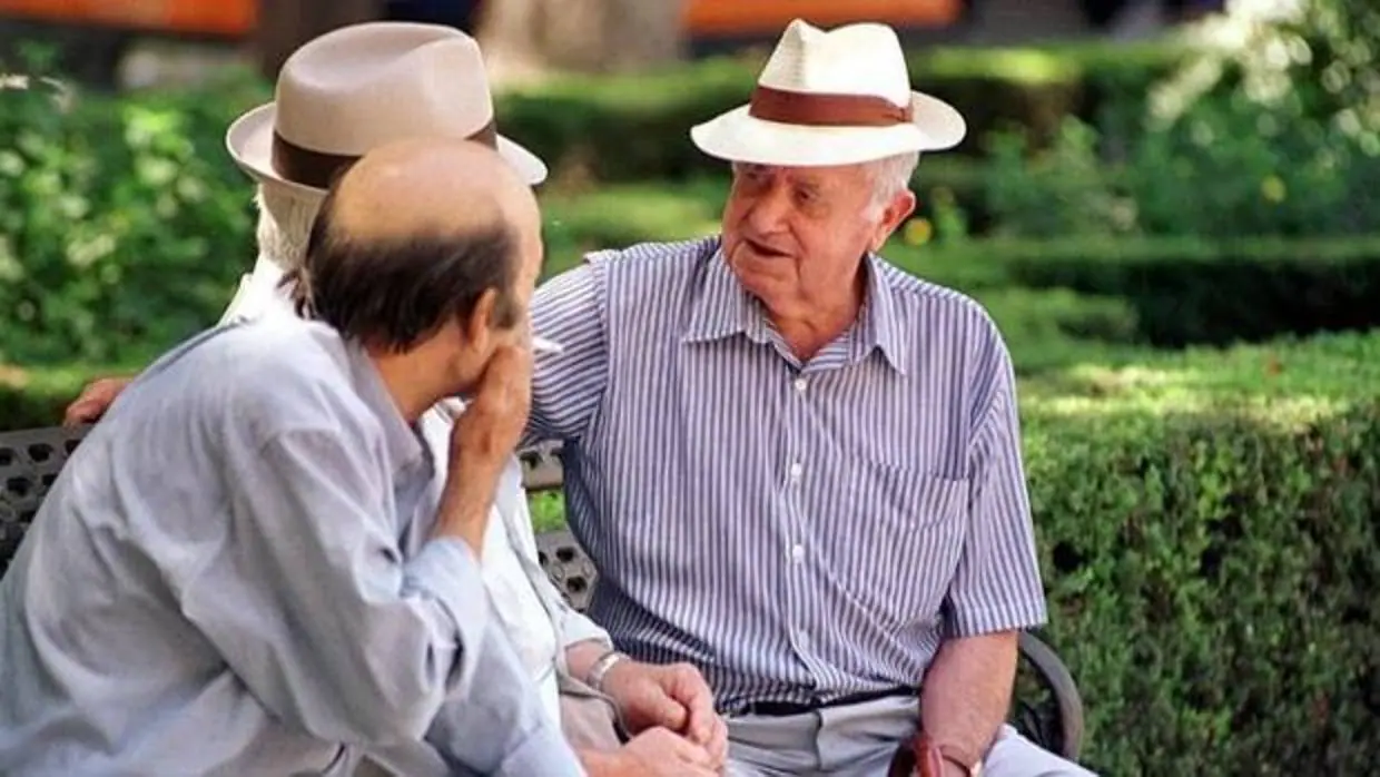 Tres ancianos, en una imagen de archivo, conversan sentados en un parque
