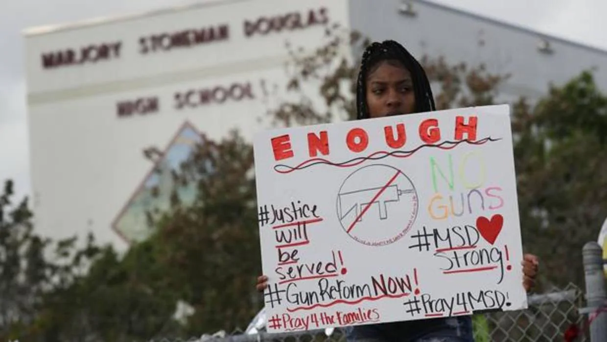 Una joven sostiene un cartel que dice «Suficiente, no armas», frente a la escuela donde se produjo el tiroteo