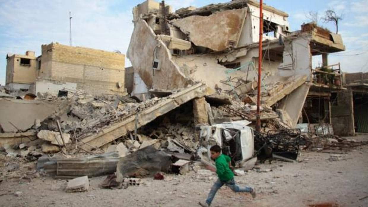 Un niño corre frente a los restos de un edificio tras los bombardeos en Guta oriental, a las afueras de Damasco