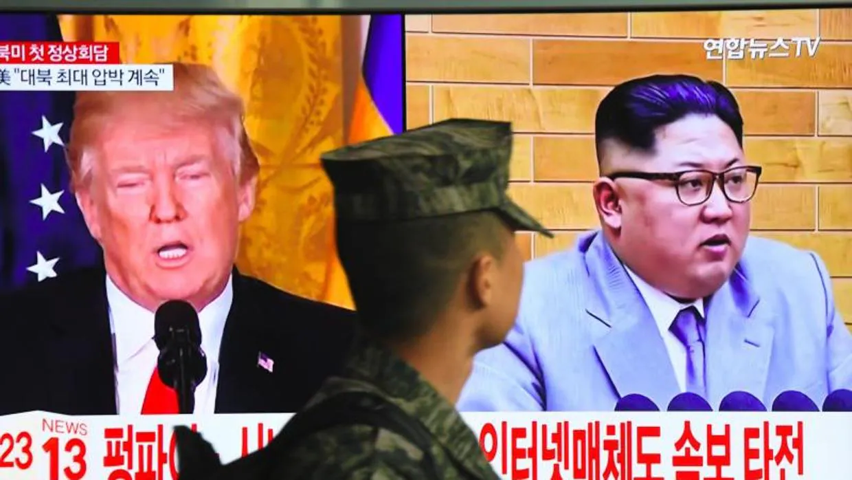 Un soldado surcoreano pasa junto a una pantalla de televisión con las imágenes de los mandatarios de EE.UU. y Corea del Norte