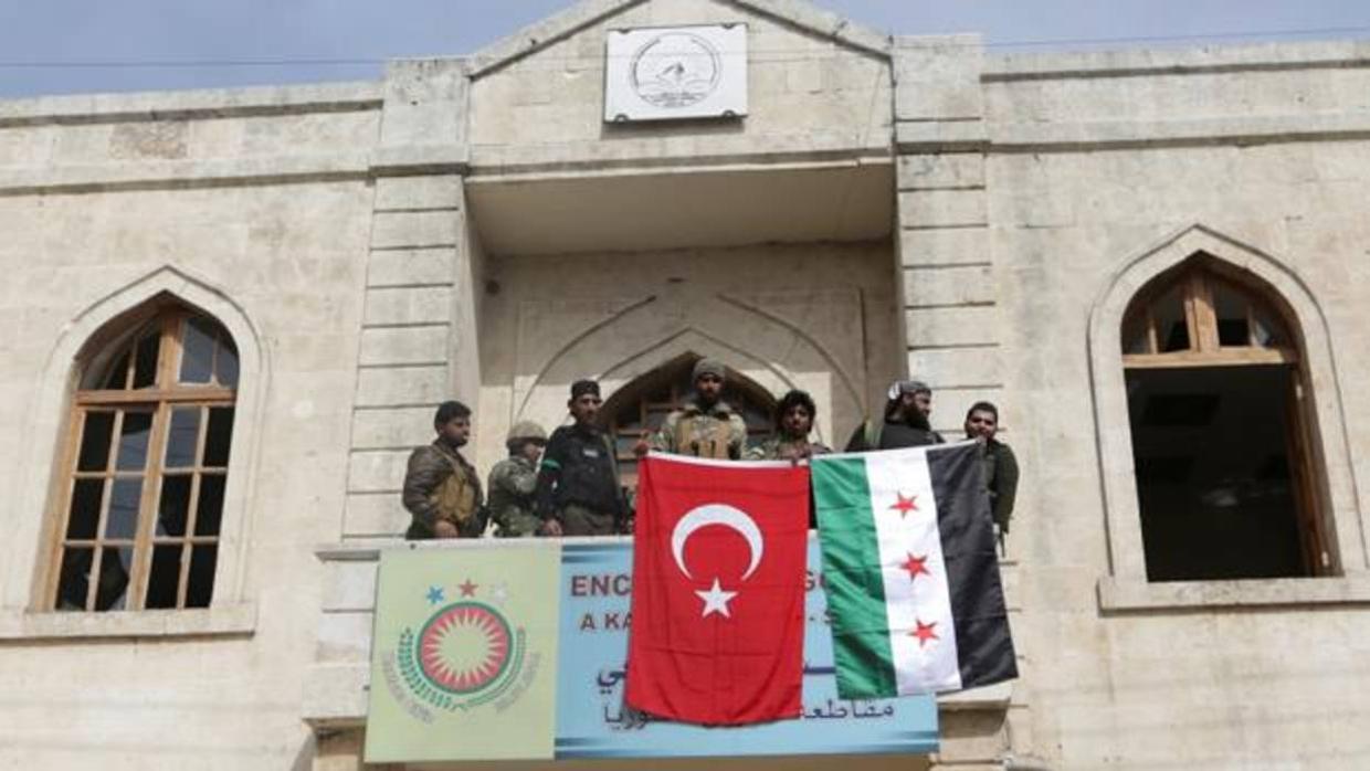 Miembros de las fuerzas turcas y del Ejército Sirio Libre posan con las banderas desplegadas en Afrín