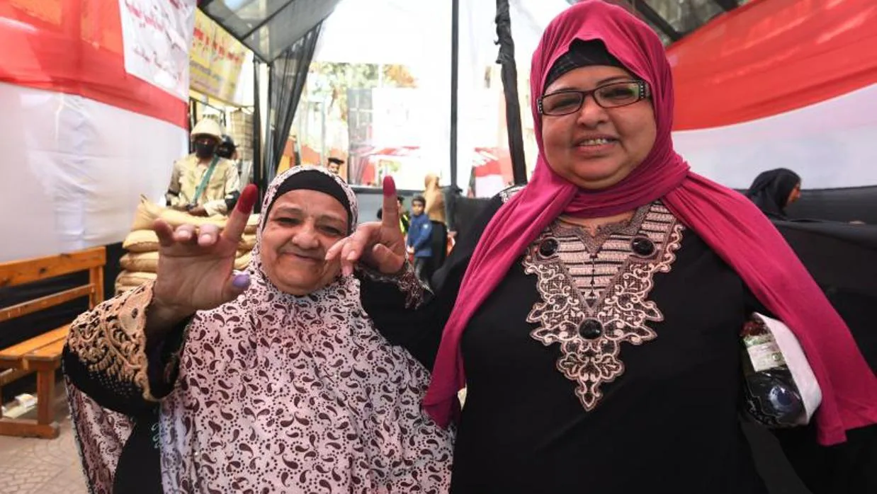 Dos mujeres muestran el dedo manchado de tinta tras votar en el barrio de Abdin, este lunes en El Cairo