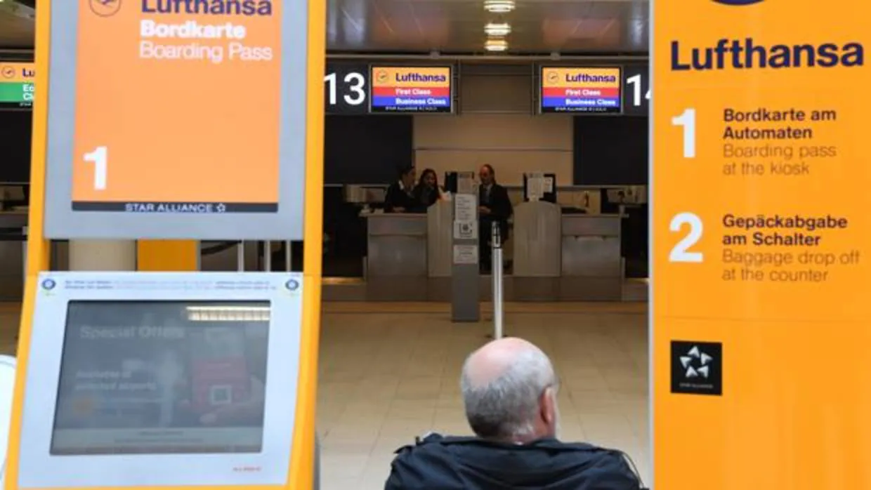 Un viajero se sienta al lado de un mostrador de facturación de Lufthansa
