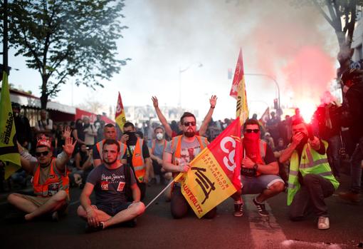 Empleados de la compañía ferroviaria estatal francesa SNCF y miembros del sindicato CGT se sientan en la acera durante una manifestación contra los planes de reforma del gobierno francés como parte de un día nacional de protesta, en París