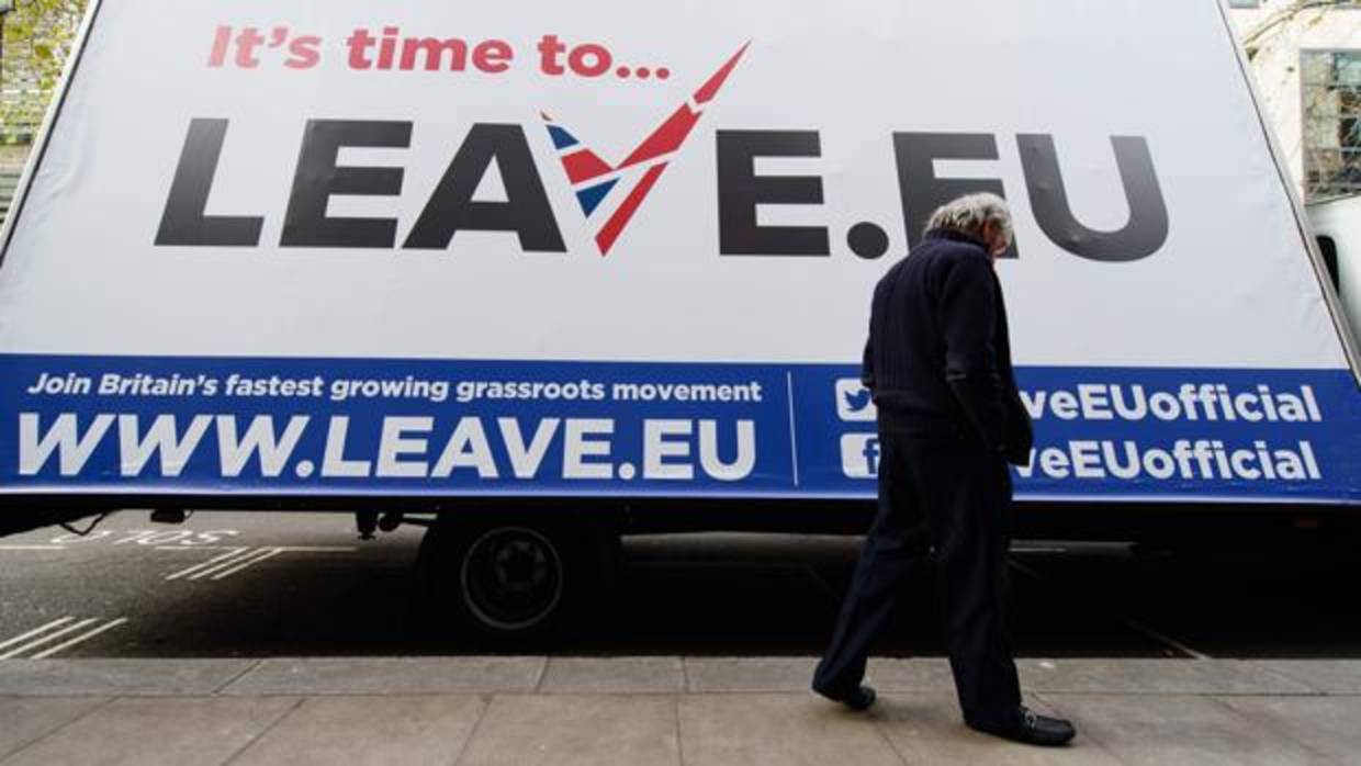 Un hombre camina frente a un cartel del grupo Leave.EU