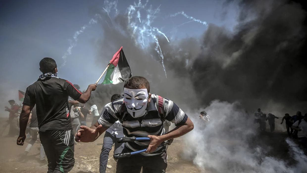 Manifestantes corren para protegerse del gas lacrimógeno lanzado por soldados israelíes