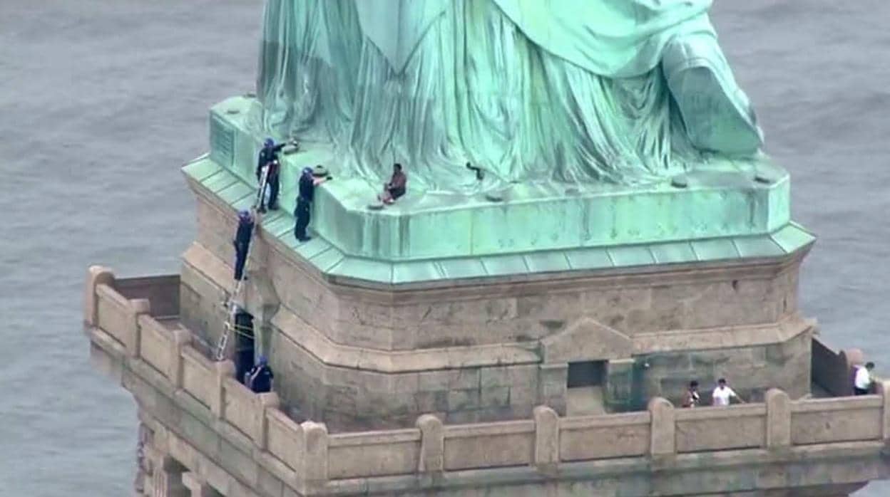 Se observa a la mujer que escala la estatua de la libertad