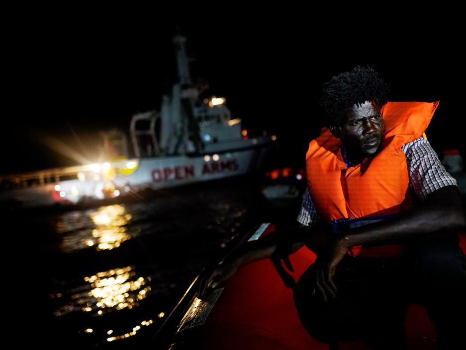 Un migrante se sienta a bordo del barco de rescate de la ONG Proactiva Open Arms en el mar Mediterráneo central