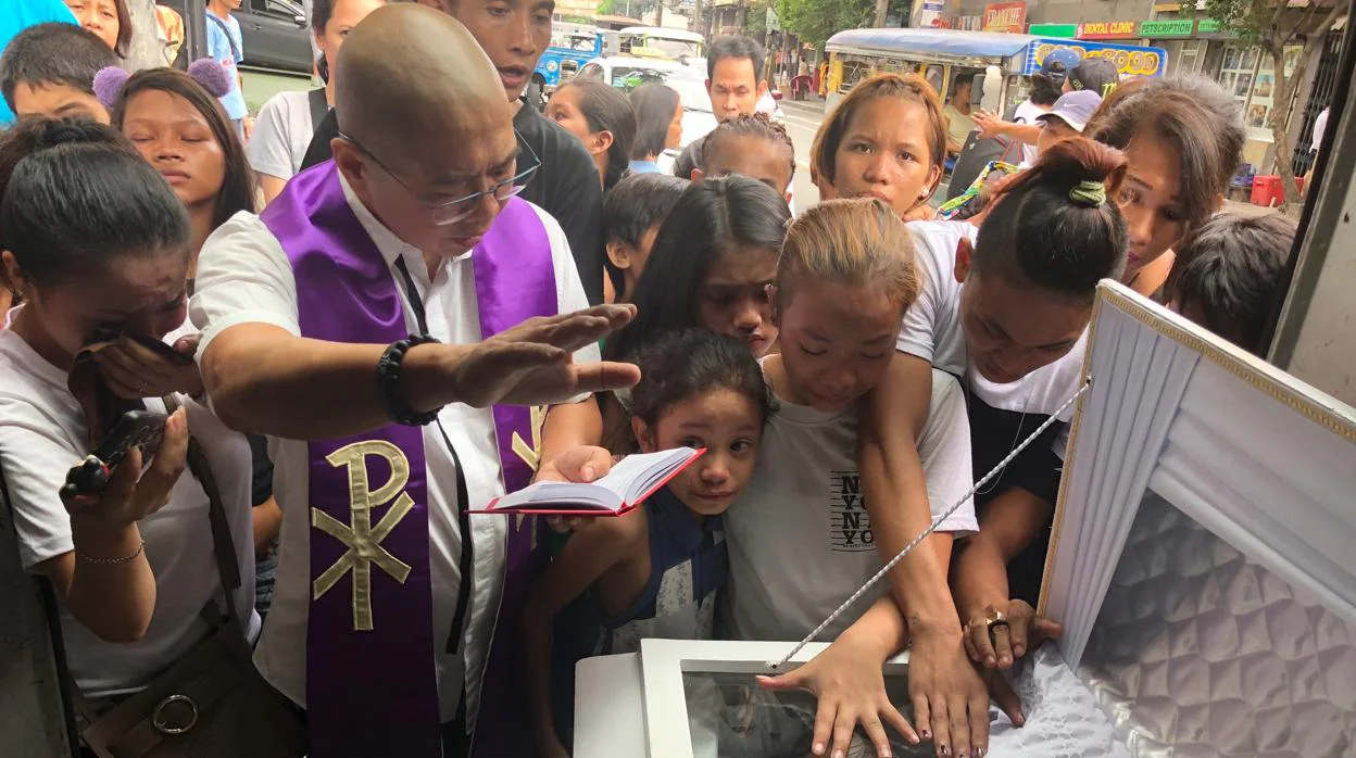 El padre Flavie Villanueva reza un responso junto al cadáver de Roberto Manaligán, abatido en la «guerra sucia» contra las drogas