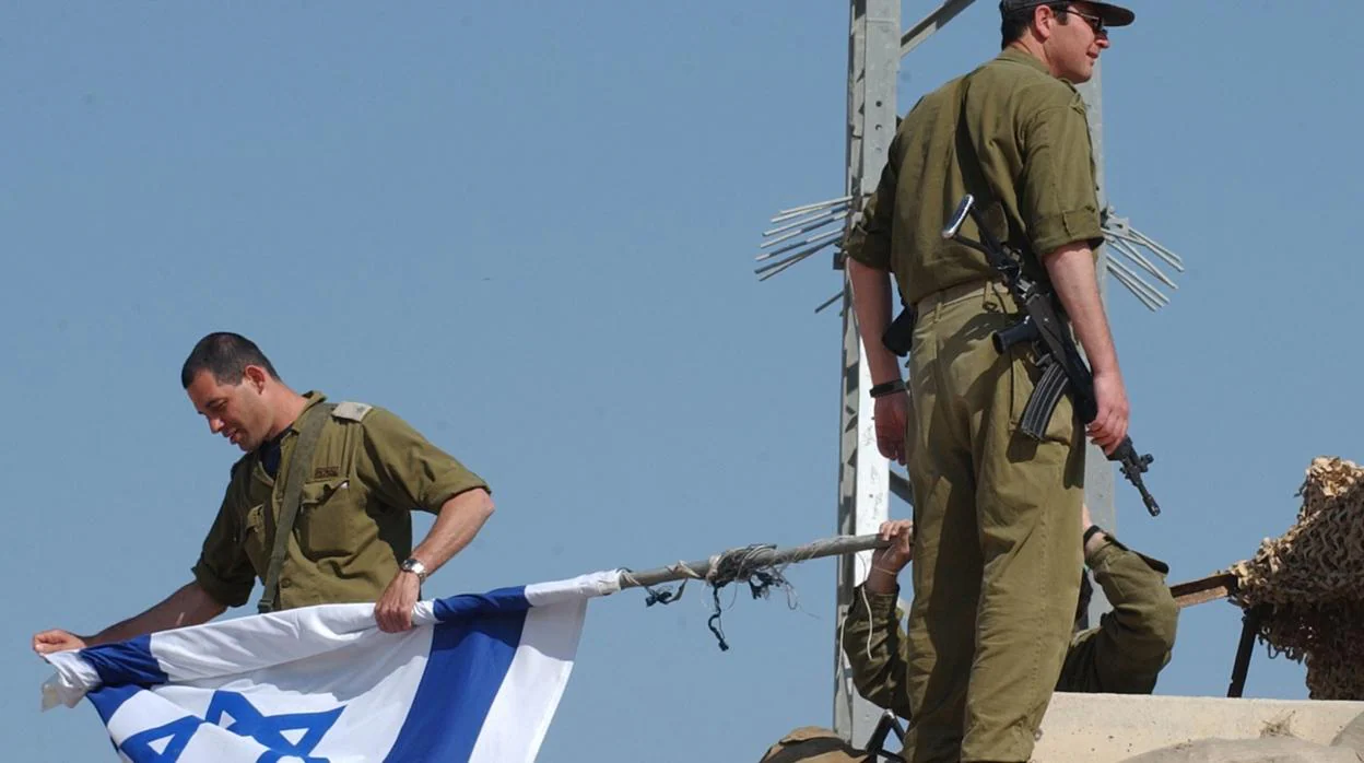 Un grupo de militares israelíes con una bandera de Israel cerca de Gaza