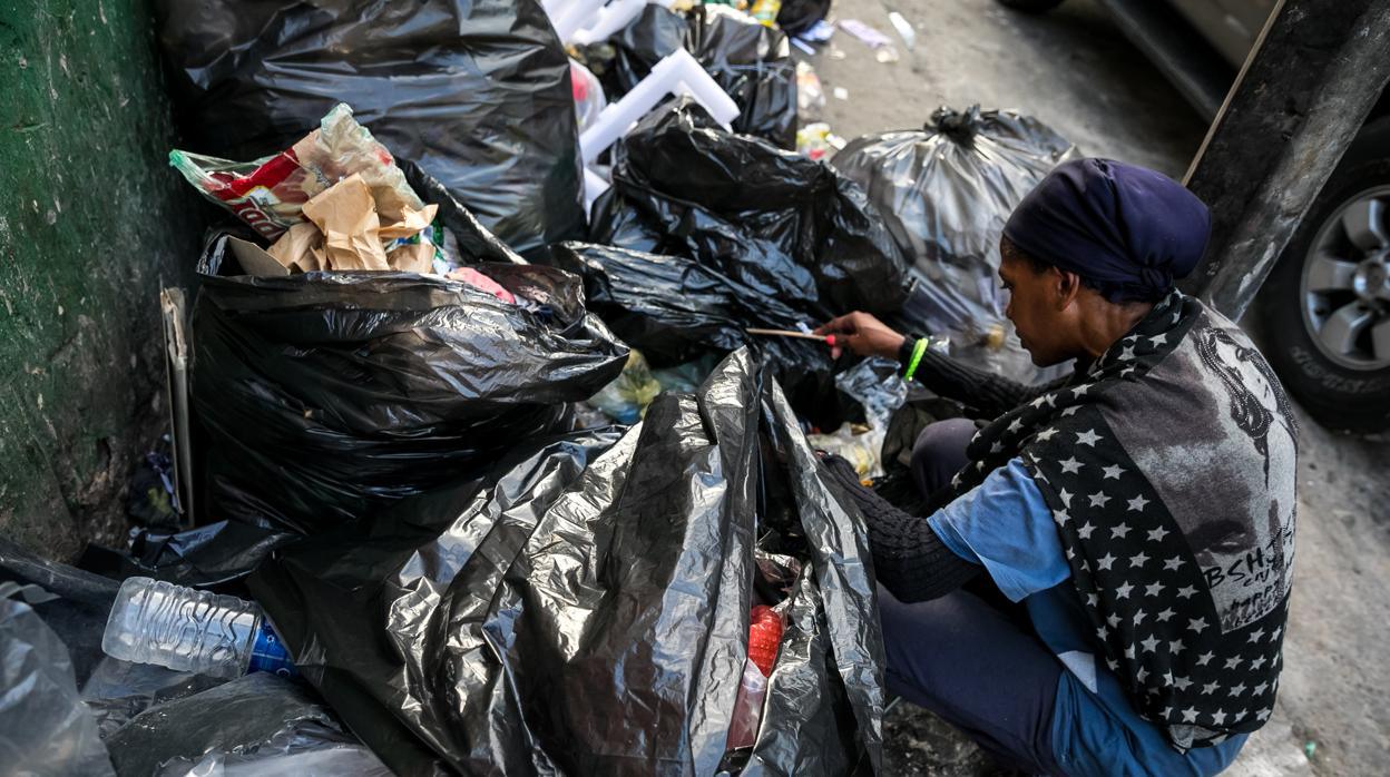 Una mujer mientras hurga en la basura en busca de comida en una calle de Caracas