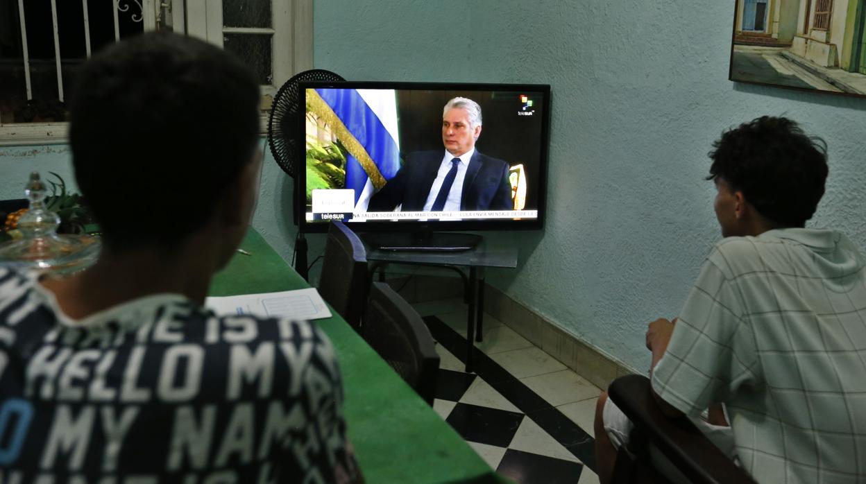 Dos jóvenes ven la entrevista al presidente cubano, Miguel Diaz-Canel, de la cadena de televisión TeleSur