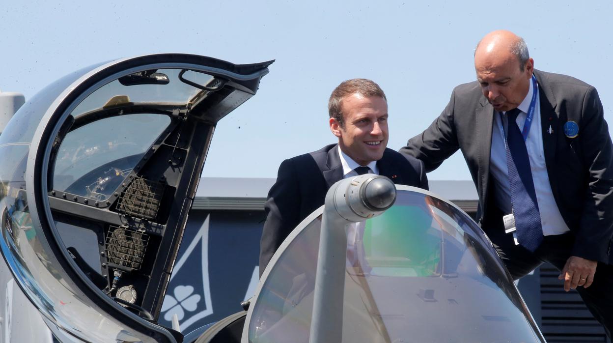 El presidente francés Emmanuel Macron sale de la cabina de un avión de combate Rafale ayudado por el CEO de Dassault Aviation Eric Trappier (R) durante su visita al 52º Salón Aeronáutico de París en Le Bourget