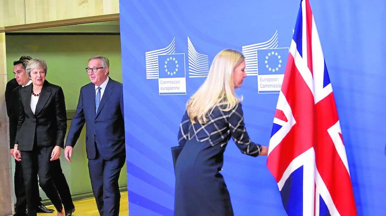 Un miembro del personal ajusta la bandera británica cuando la primera ministra británica Theresa May y el presidente de la Comisión Europea, Jean-Claude Juncker, llegan a la sede de la CE en Bruselas