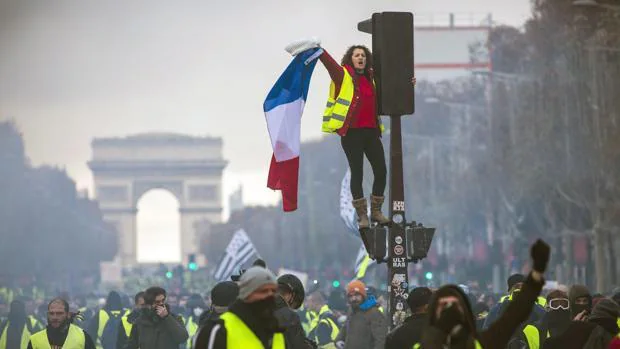 Una mujer grita consignas subida a un semáforo durante una protesta en los Campos Elíseos en París