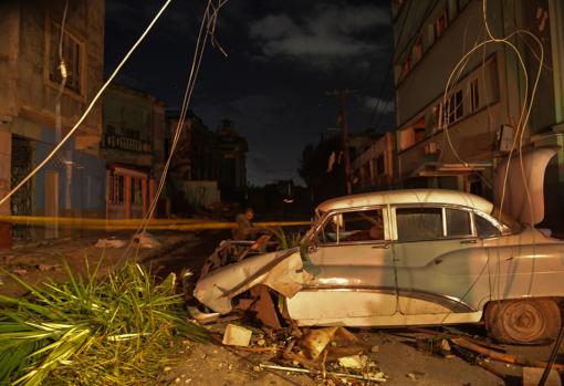 Un coche dañado y postes de electricidad caídos