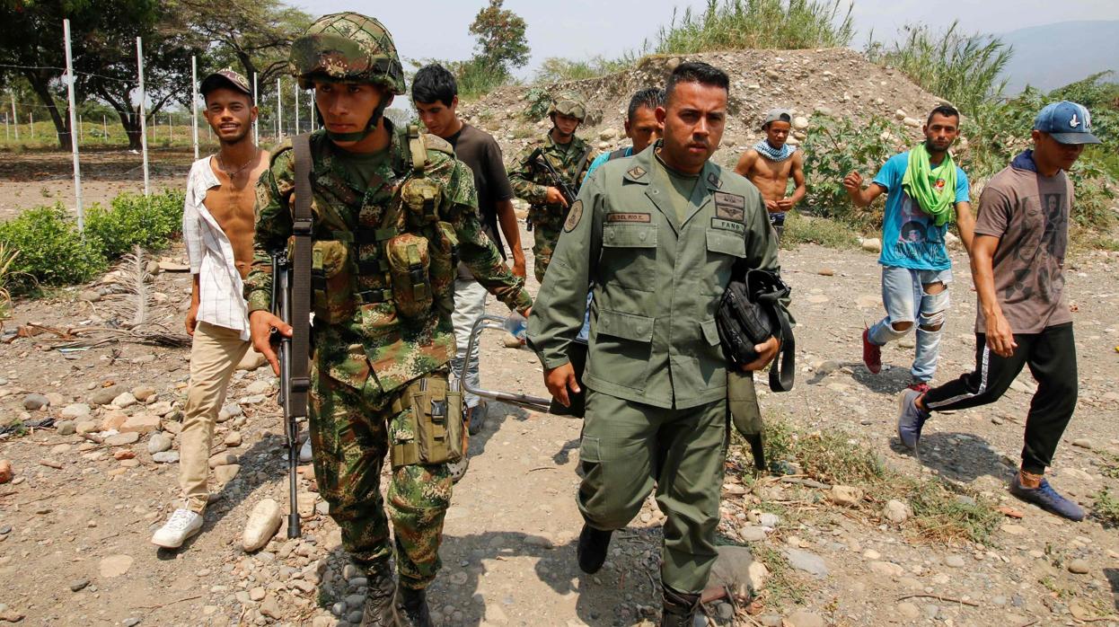 Un soldado colombiano acompaña a uno de los guardias venezolanos que abandonan a Maduro