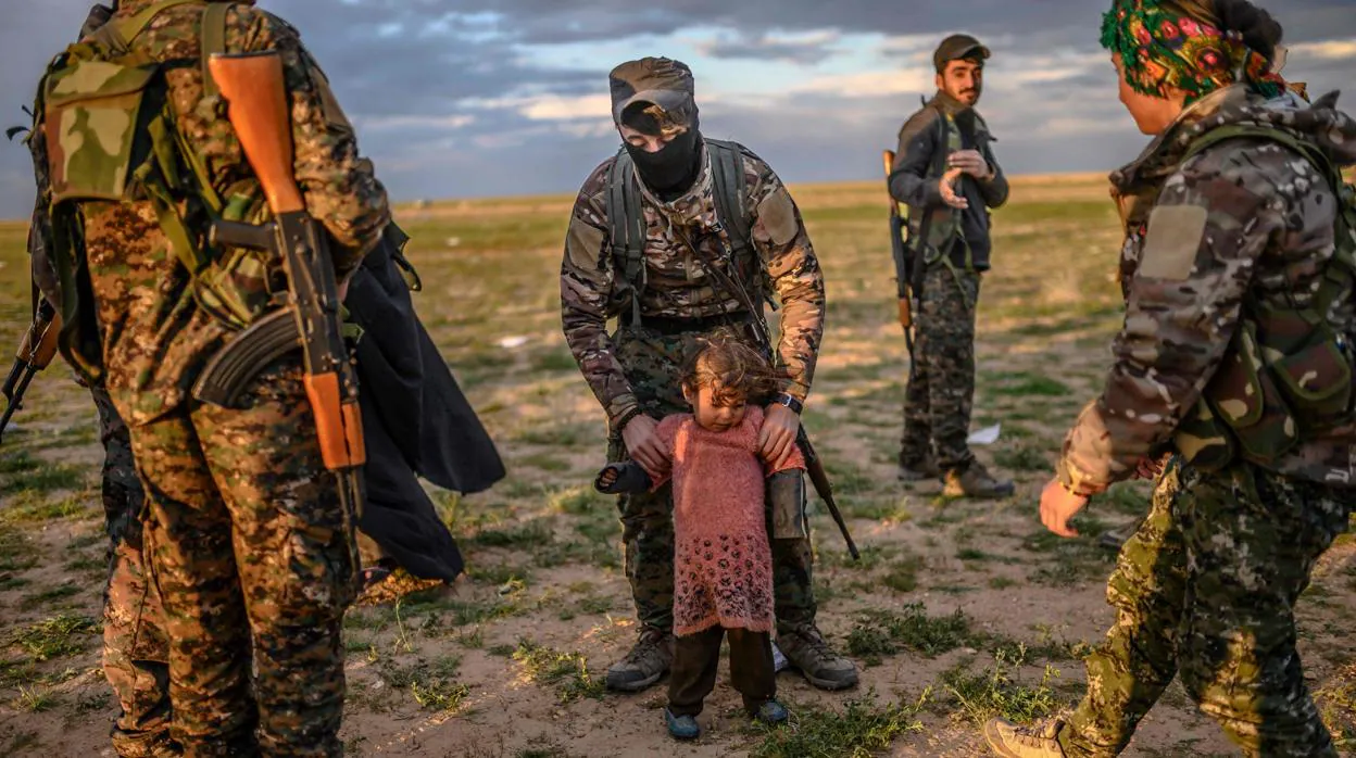 Soldados kurdos que cercan Baghouz con una niña que forma parte de los civiles evacuados