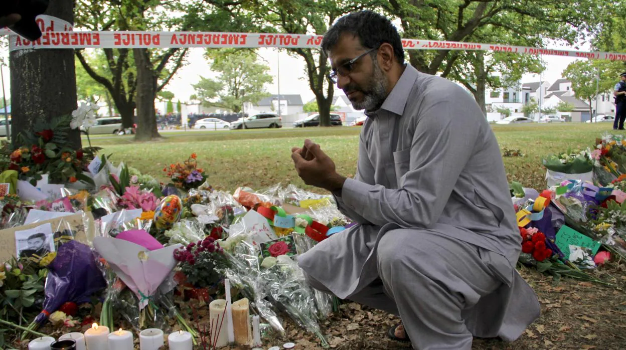 Tras sobrevivir de milagro, el afgano Mirwais reza antes las flores y retratos que recuerdan a las víctimas del ataque islamófobo contra las mezquitas de Christchurch