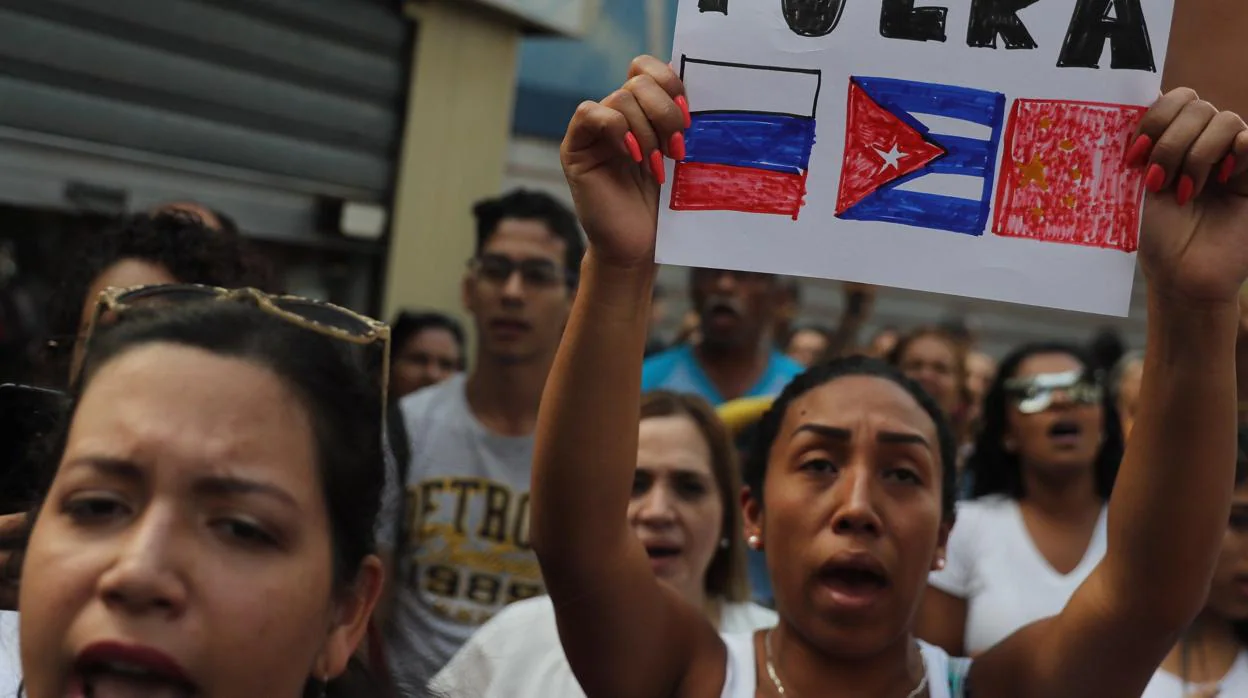 Una mujer en Caracas sostiene una pancarta donde pide que Rusia, Cuba y China se alejen del país