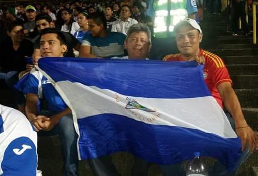 De izquierda a derecha, Kevin y su padre Roberto, junto a un amigo, durante un partido de fútbol con la bandera de Nicaragua