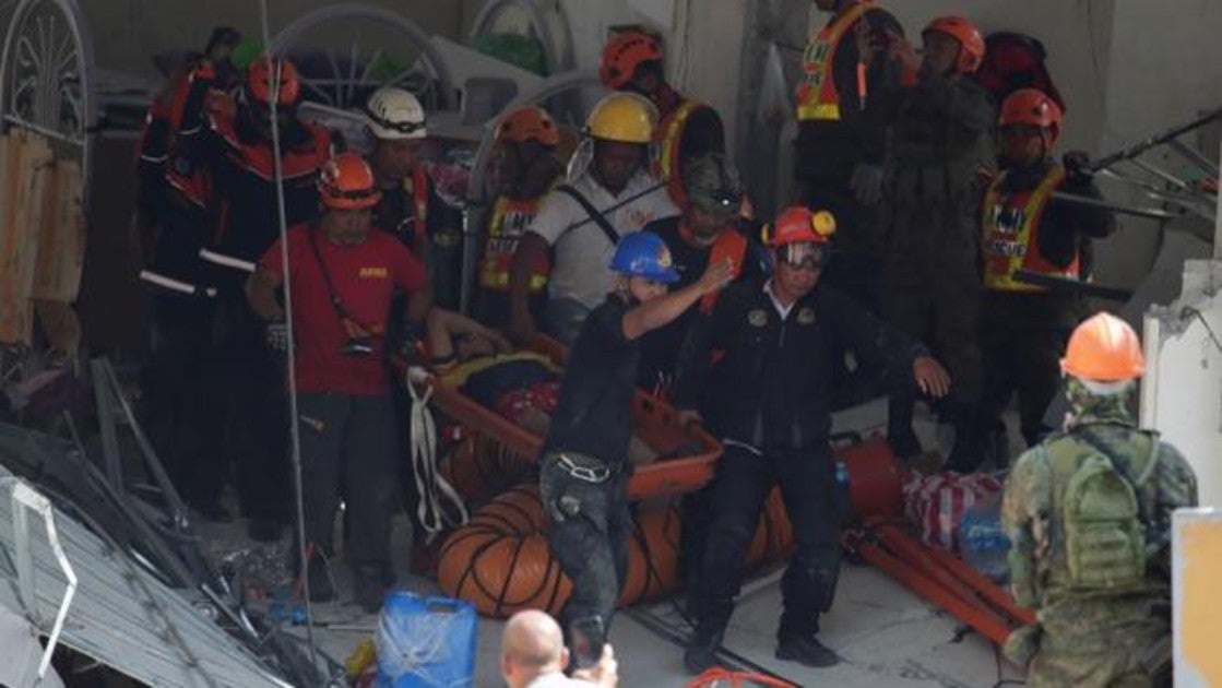 Personal de emergencia ayuda a un herido en un edificio comercial que colapsó tras el terremoto