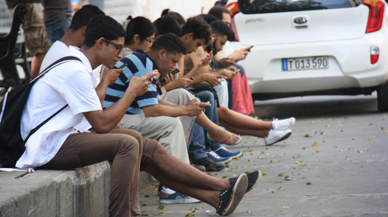 Cubanos consultan sus teléfonos móviles en un punto con internet en La Habana