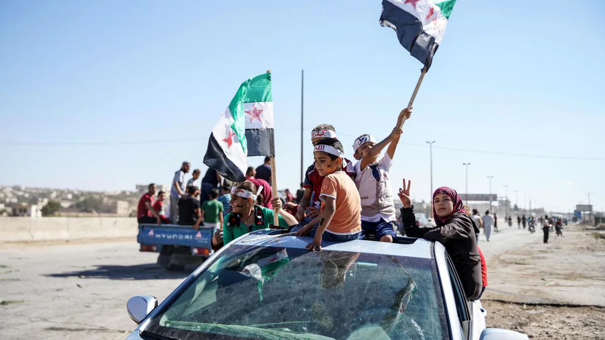 Varias personas ondean banderas sirias revolucionarias durante una protesta en la localidad de Kafr Nabl, en la provincia de Idlib