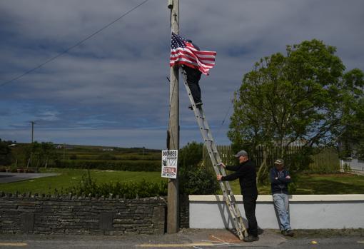 Unos vecinos instalan una bandera de EE.UU. en un poste de una calle de Doonbeg