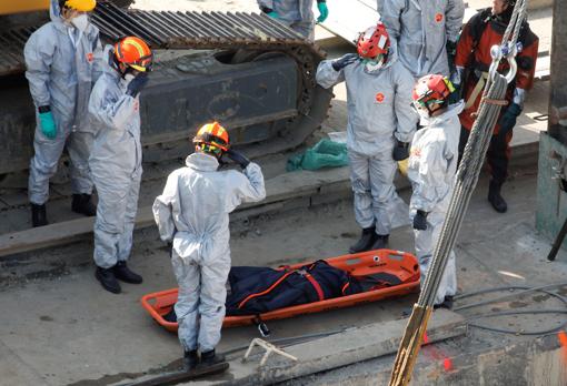 Miembros de los servicios de rescate ante el cuerpo de una de las víctimas mortales del barco naufragado en el río