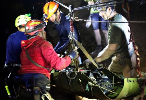 Varios miembros del equipo de rescate evacuan a uno de los niños