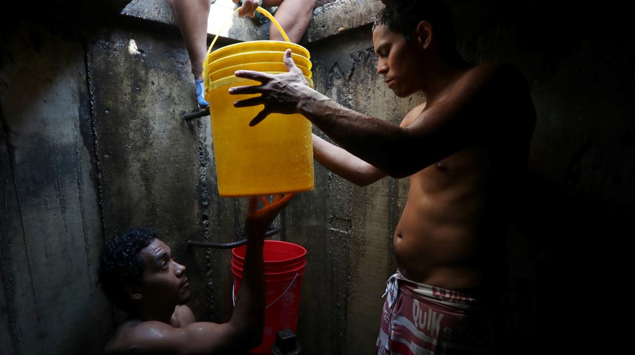 Vecinos de Caracas cogen agua de una tubería subterránea