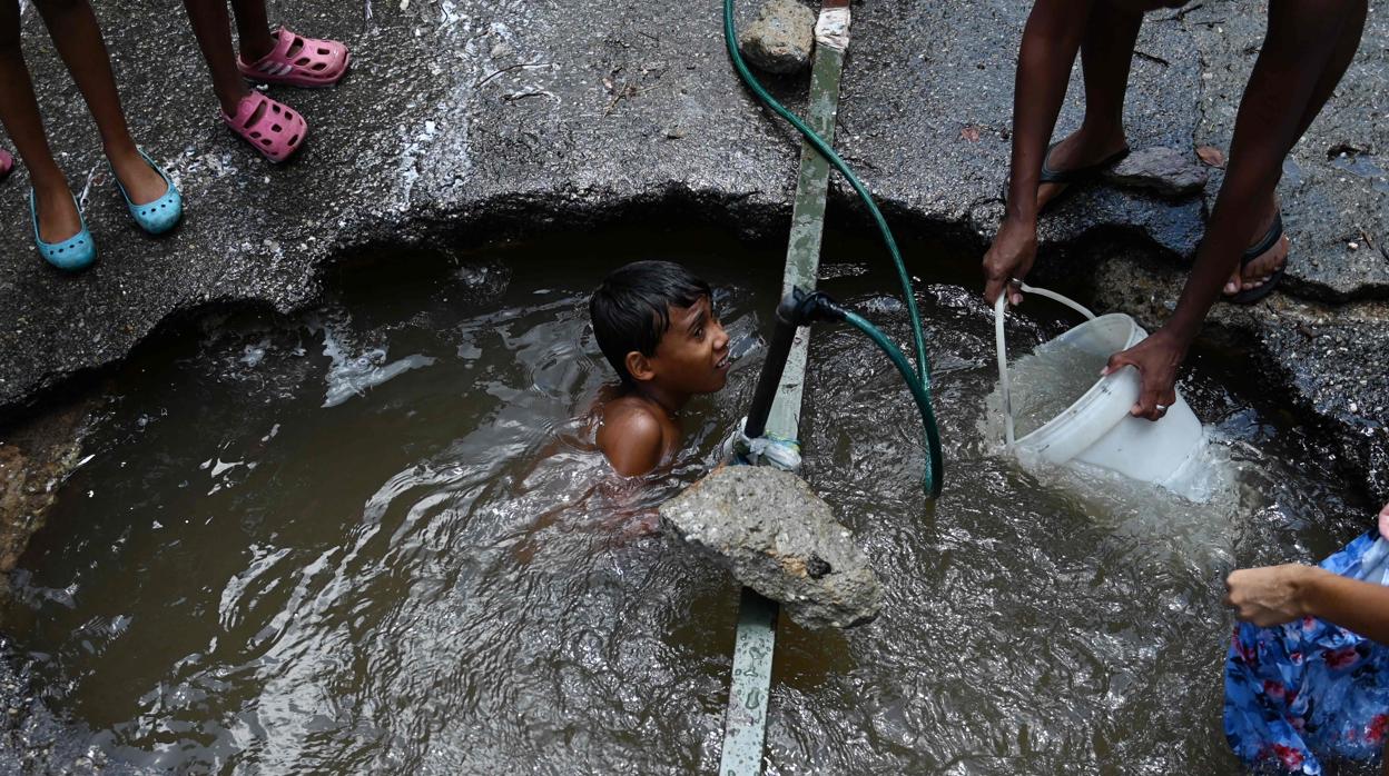 Un niño se baña en una poza en una calle de Caracas, el pasado mayo