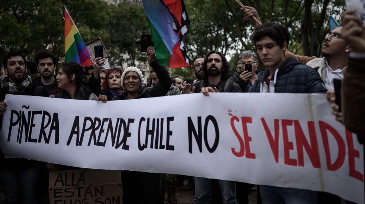 Los manifestantes sostienen una pancarta en contra del presidente de Chile