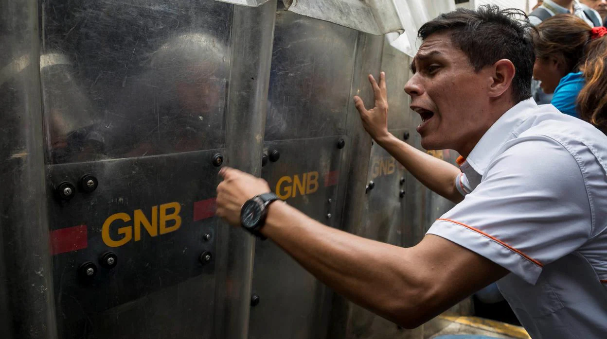 Un venezolano protesta frente a varios agentes de la Guardia Nacional Bolivariana