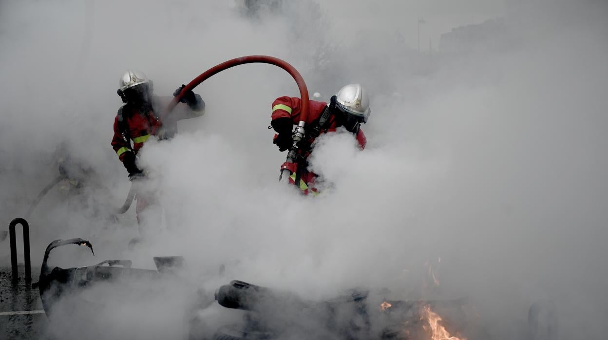 Los bomberos apagan una motocicleta incendidada en la Plaza de Italia en París durante las protestas de los «chalecos amarillos»