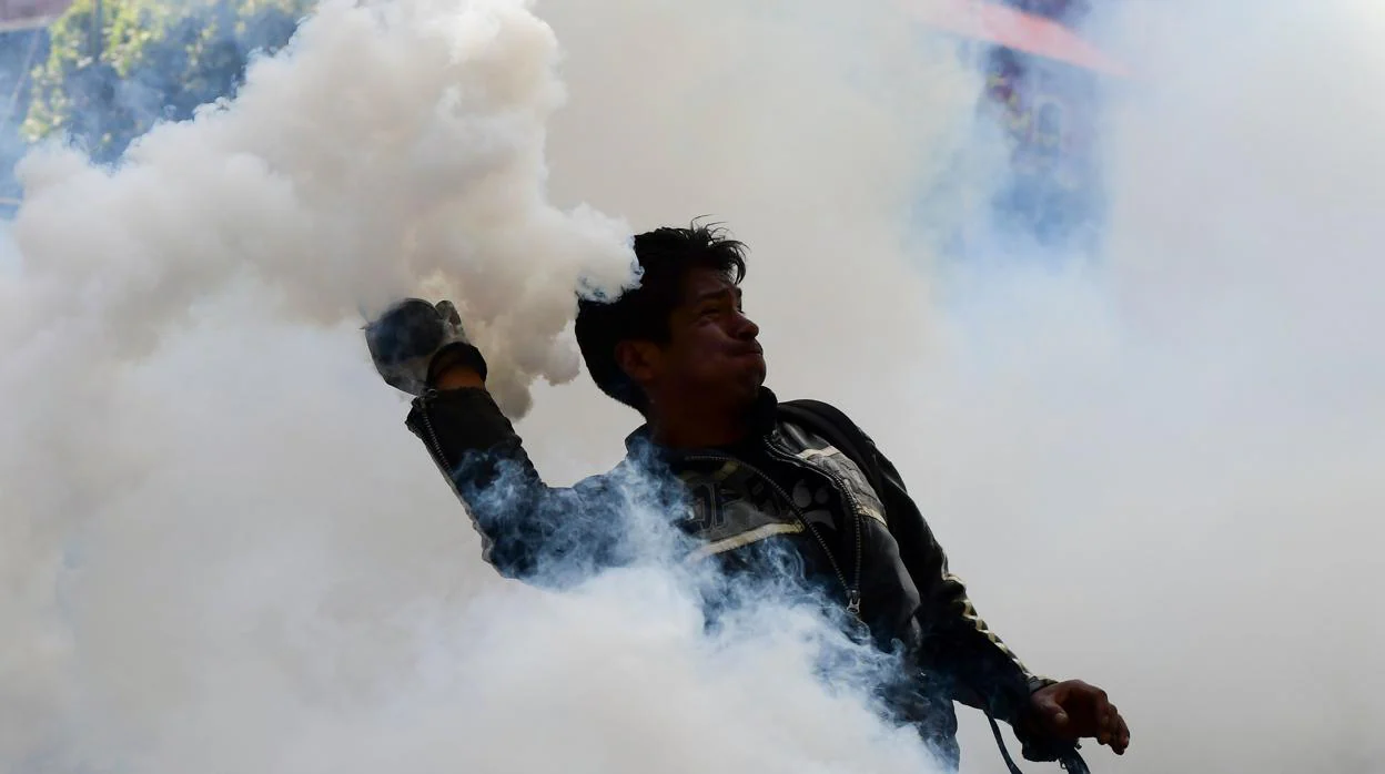 Un seguidor del expresidente Evo Morales devuelve este viernes una carga de gas lacrimógeno durante una protesta contra el gobierno interino, en La Paz