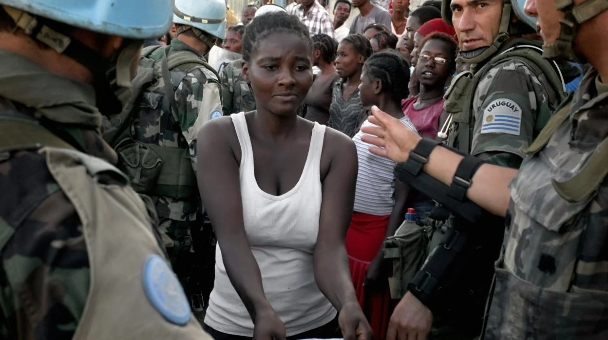 Una mujer pasa entre «cascos azules» de la ONU en 2010 en Haití