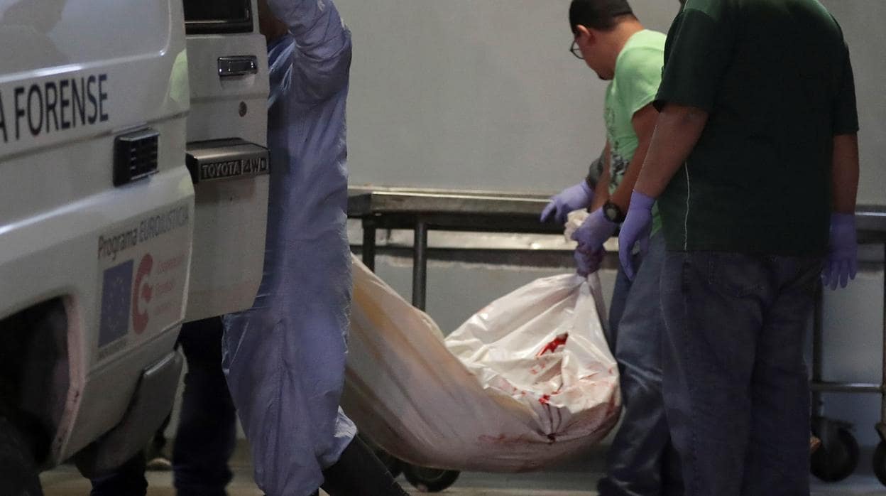 Técnicos de medicina forense trasladan uno de los cuerpos de uno de los presos muertos