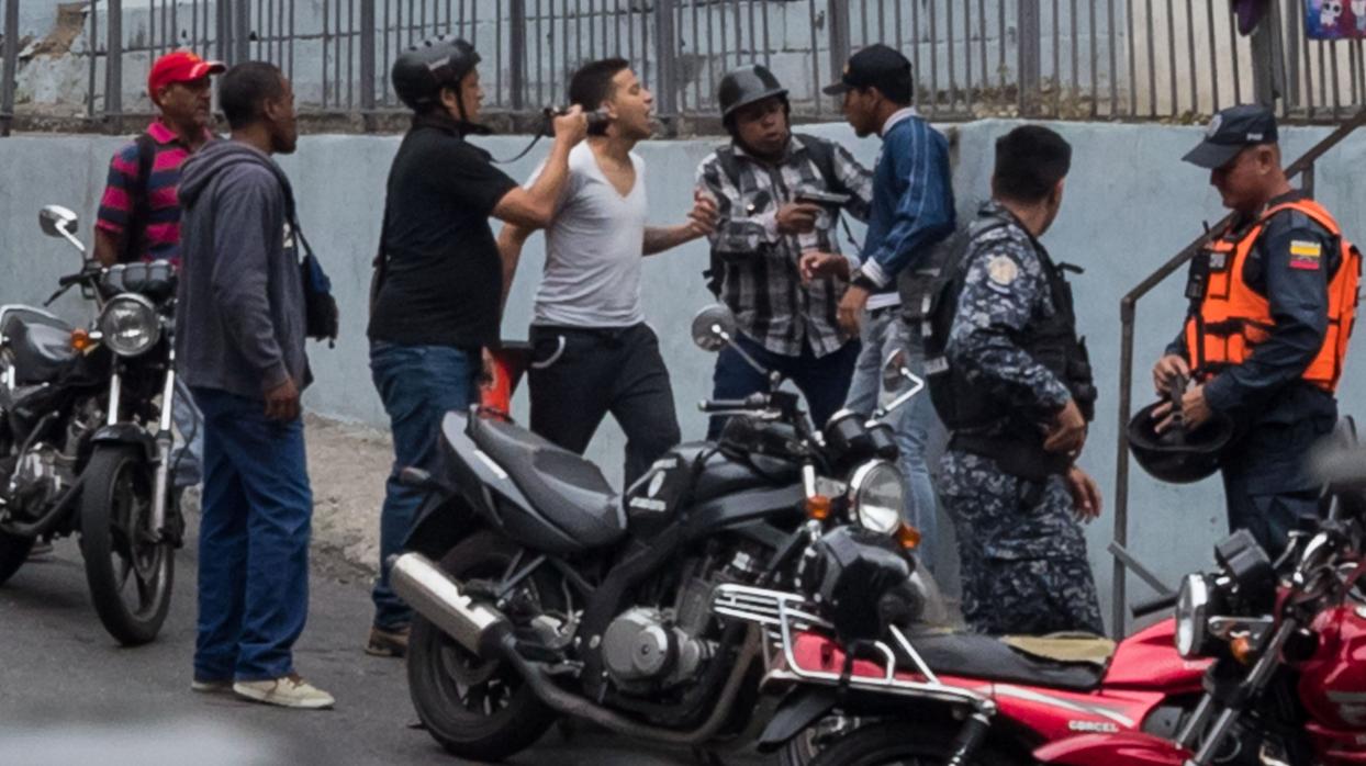 Oswaldo Rivero graba a un joven con su cámara mientras otro lo apunta con una pistola