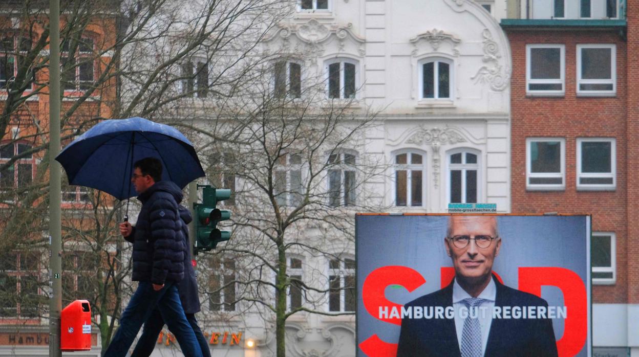 Dos personas pasan por delante de un cartel electoral del SPD, en Hamburgo