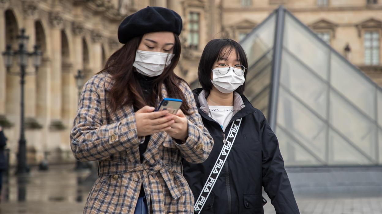 Dos mujeres se cubren el rostro con una mascarilla en los alrededores del Museo del Louvre