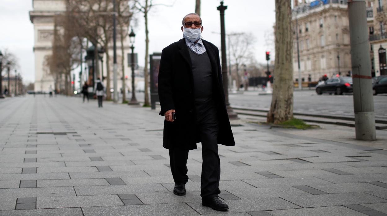 Un hombre pasea por la Avenida de los Campos Elíseos de París, vacía ante la crisis sanitaria