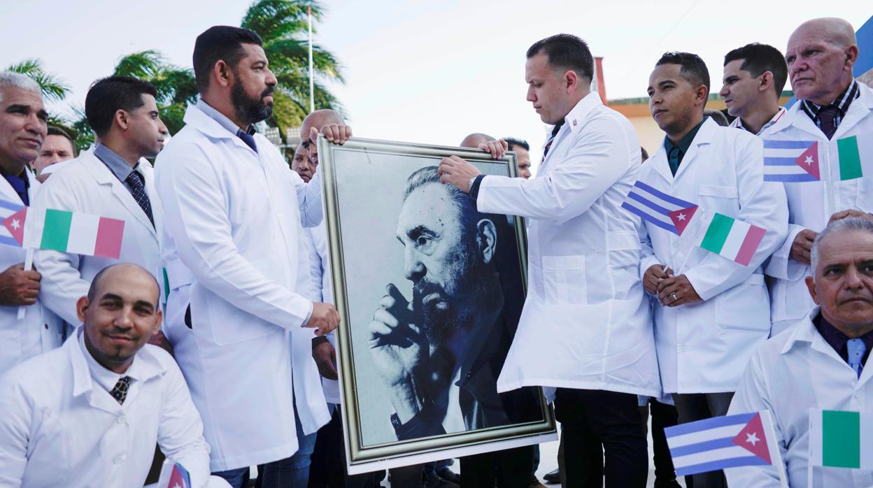 Médicos cubanos sostienen una imagen de Fidel Castro durante el acto de despedida antes de partir hacia Italia