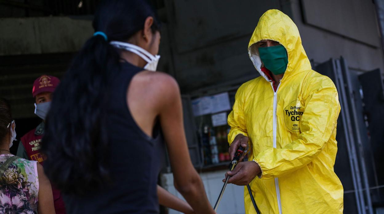 Un operario desinfecta las manos de una cliente de un mercado municipal