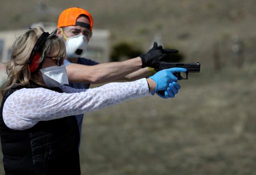 Una mujer sigue las indicaciones de un instructor durante unas prácticas de tiro en Colorado