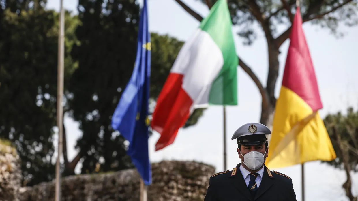 Un policía italiano se para frente a una bandera de Italia y la Unión Europea